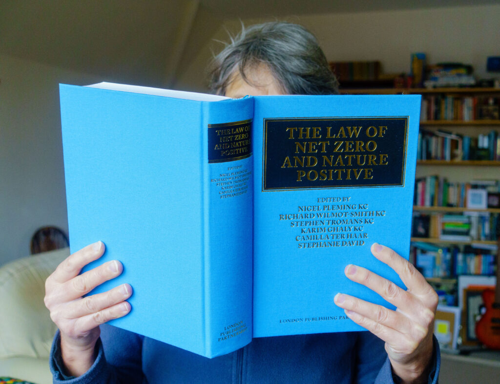 Woman holding a large blue law text book up in front of her face.